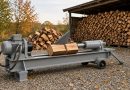 Hydraulický štípač na dřevo na dvoře s hromadou naštípaných polen